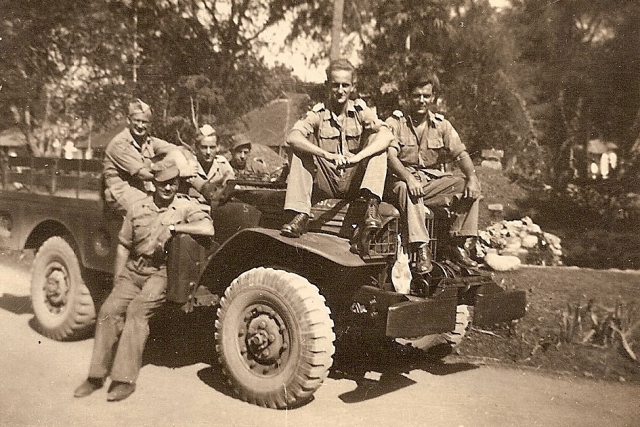 Voor het bat.-bureau in Denpasar - Bali, Voorop: vlnr Jan van Trigt, Joop Huijsmans. Naast zittend: Broer Bolk, vlnr in de wagen: Piet Buysrogge, Eddy Groenhof en Jan van Vonno, oktober 1946.
