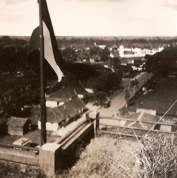 Zicht vanaf de watertoren in Palembang over de Raadhuisweg in de richting van de (witte) moskee; daar tussenin staat de gevangenis. De Nederlandse vlag wappert. Rechts het voetbalveld achter de benteng.